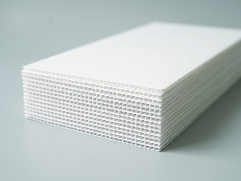 A stack of blank white Correx sheets, the fluted core visible along the cut edge.